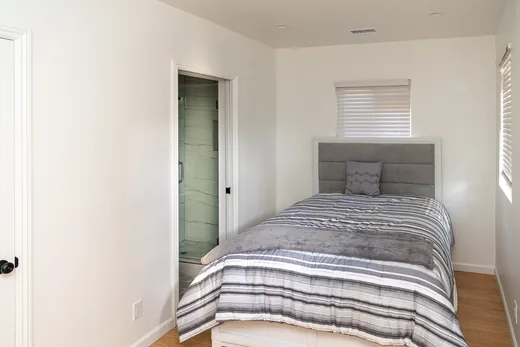 Bedroom with striped bedding and access to a closet and bathroom