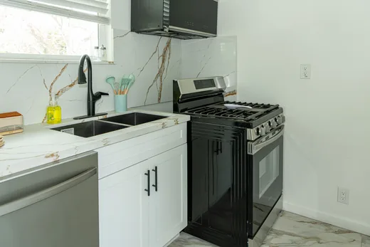Kitchen sink below a window with a black gas range alongside